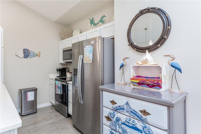 kitchen featuring white cabinetry, baseboards, light wood-style floors, light countertops, and appliances with stainless steel finishes