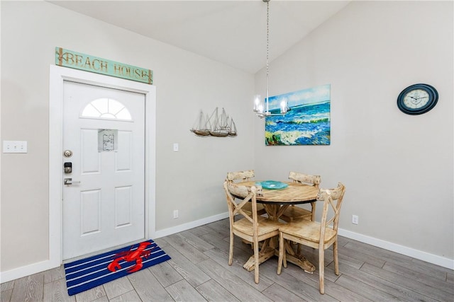 dining room with lofted ceiling, an inviting chandelier, baseboards, and wood finished floors