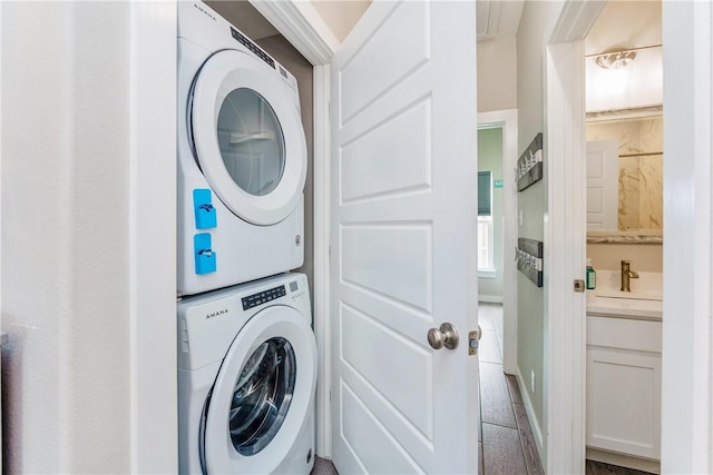 clothes washing area featuring stacked washer and dryer, laundry area, and a sink