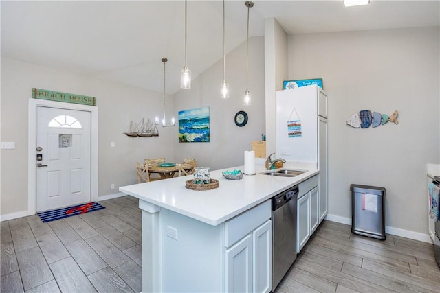 kitchen with wood finish floors, a sink, a peninsula, and stainless steel dishwasher