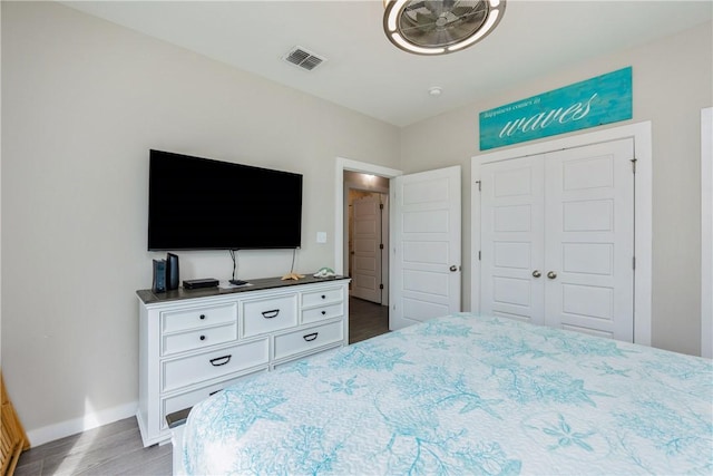 bedroom with baseboards, a closet, visible vents, and wood finished floors