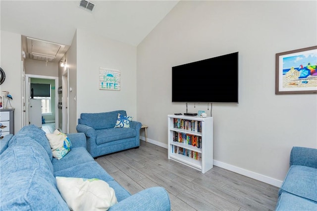 living room featuring visible vents, attic access, vaulted ceiling, wood finished floors, and baseboards