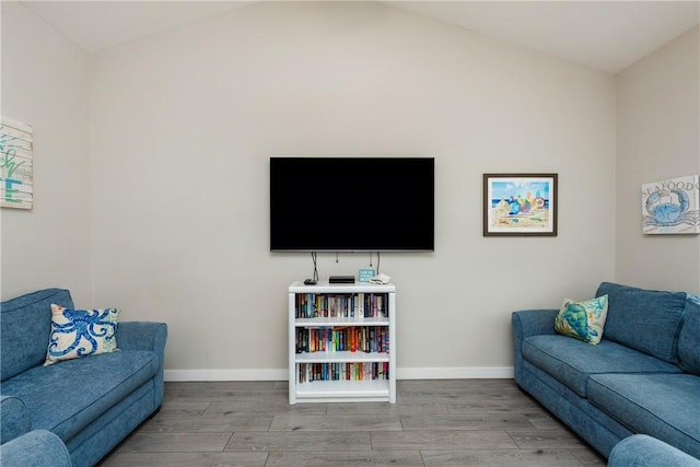 living area featuring baseboards, vaulted ceiling, and wood finished floors