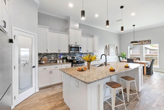 5810 Bella Di Giorno Dr, Corpus Christi, TX 78414 - kitchen with appliances with stainless steel finishes, decorative backsplash, light wood-style floors, white cabinetry, and ornamental molding