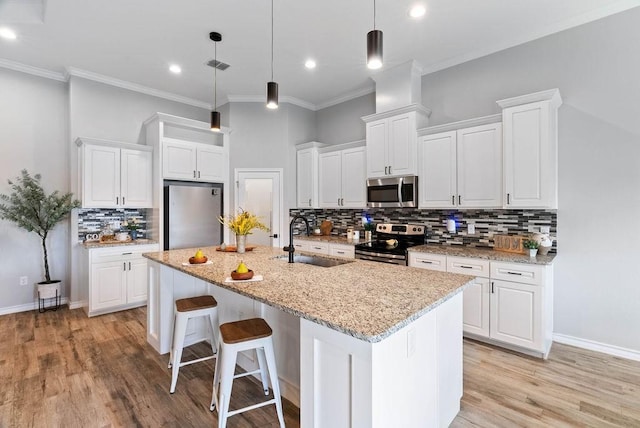 5810 Bella Di Giorno Dr, Corpus Christi, TX 78414 - kitchen featuring appliances with stainless steel finishes, backsplash, a center island with sink, white cabinetry, and crown molding