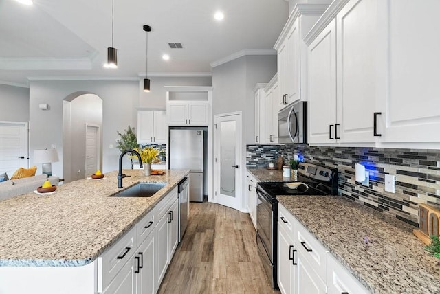 5810 Bella Di Giorno Dr, Corpus Christi, TX 78414 - kitchen featuring appliances with stainless steel finishes, arched walkways, white cabinetry, wood finished floors, and crown molding