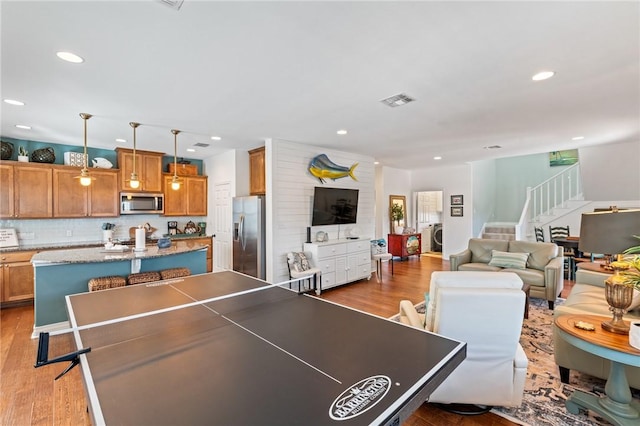 game room with washer / dryer and light wood-type flooring