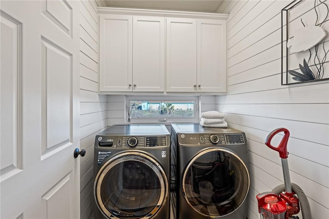 laundry area with wood walls, cabinets, and independent washer and dryer