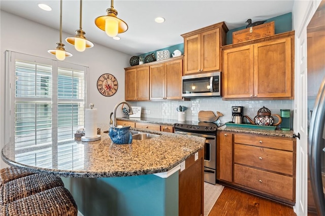 kitchen with sink, decorative backsplash, appliances with stainless steel finishes, decorative light fixtures, and light stone counters