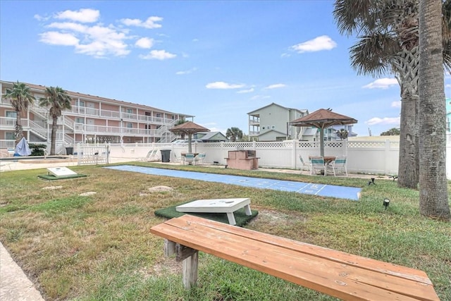 view of property's community featuring a lawn and fence