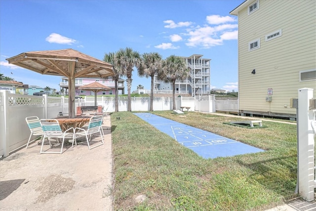 view of community with a patio area, a lawn, shuffleboard, and fence