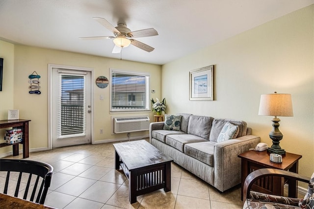 living area with a wall unit AC, light tile patterned floors, a ceiling fan, and baseboards