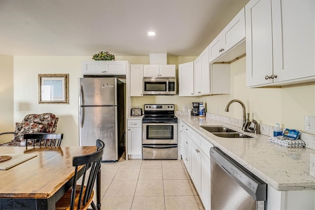 kitchen featuring a sink, appliances with stainless steel finishes, white cabinets, light tile patterned floors, and light stone countertops