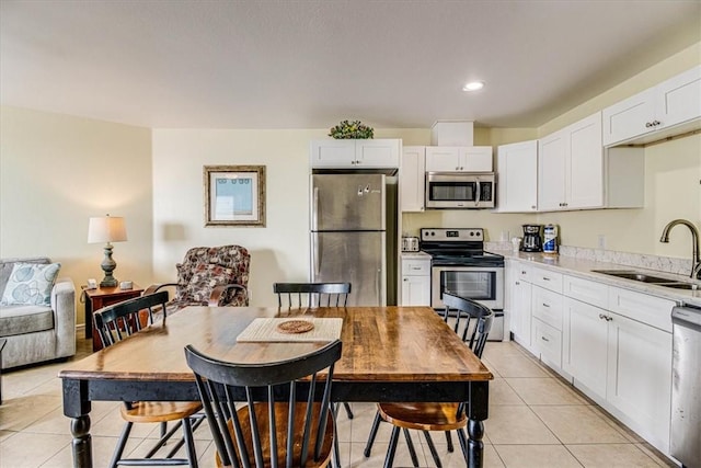 kitchen with light tile patterned flooring, appliances with stainless steel finishes, white cabinetry, and a sink