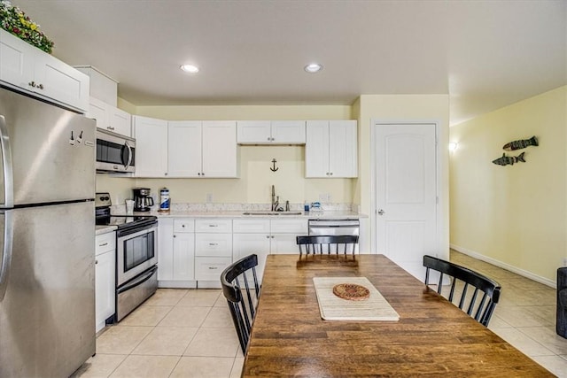 kitchen with a sink, light tile patterned flooring, white cabinetry, and stainless steel appliances