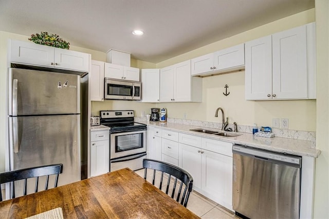 kitchen with light tile patterned flooring, white cabinets, appliances with stainless steel finishes, and a sink