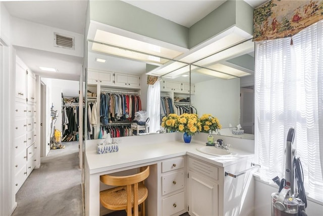 walk in closet with light colored carpet, visible vents, and a sink