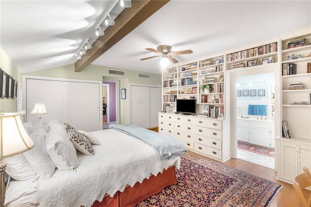 bedroom with a closet, visible vents, vaulted ceiling with beams, and wood finished floors