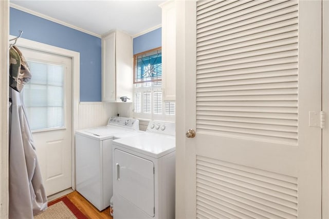 washroom featuring cabinet space, a wainscoted wall, light wood-style flooring, crown molding, and separate washer and dryer