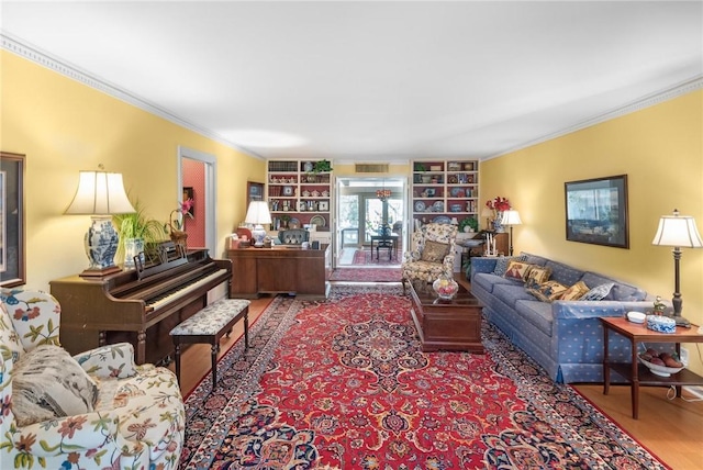 living area featuring built in shelves, ornamental molding, wood finished floors, and visible vents