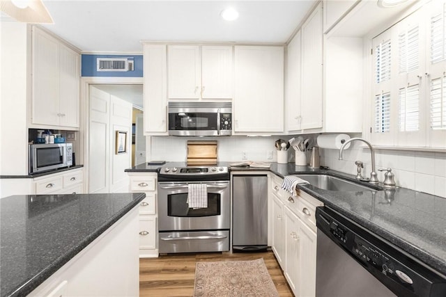 kitchen with light wood finished floors, visible vents, a sink, stainless steel appliances, and backsplash