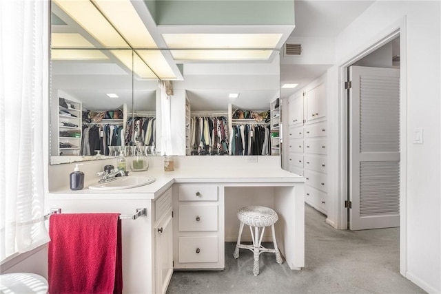 bathroom featuring a walk in closet, visible vents, and vanity