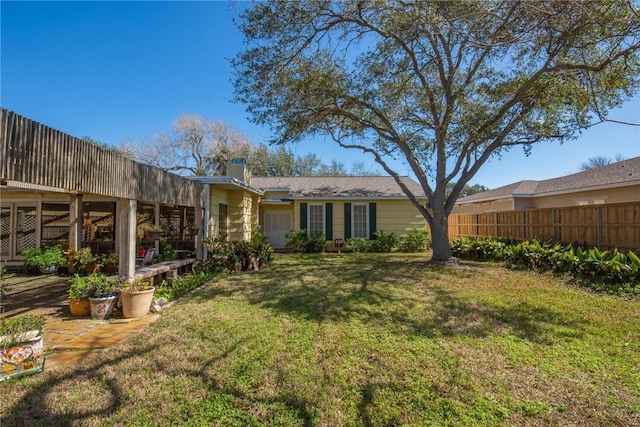 rear view of property with a chimney, fence, and a lawn