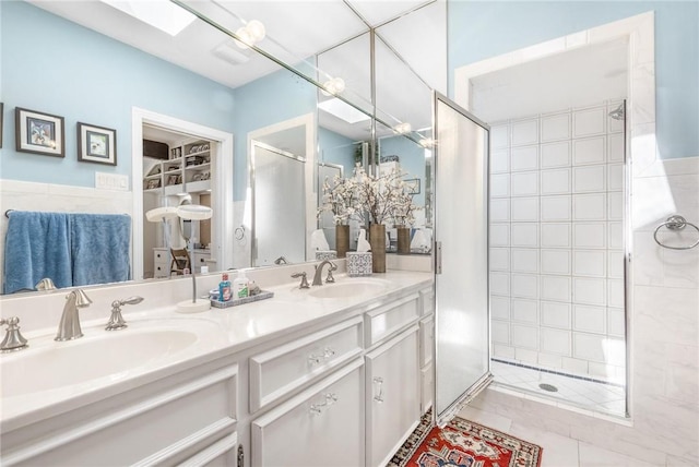 full bathroom featuring a skylight, a sink, a shower stall, and double vanity