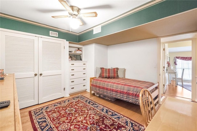 bedroom featuring ceiling fan, a closet, visible vents, and wood finished floors