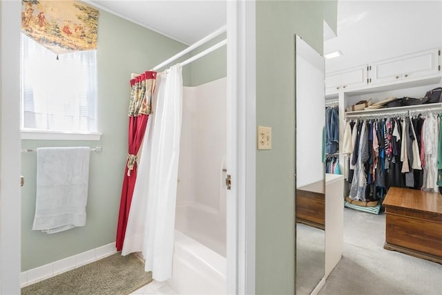 full bath featuring shower / bath combo with shower curtain, baseboards, and a walk in closet