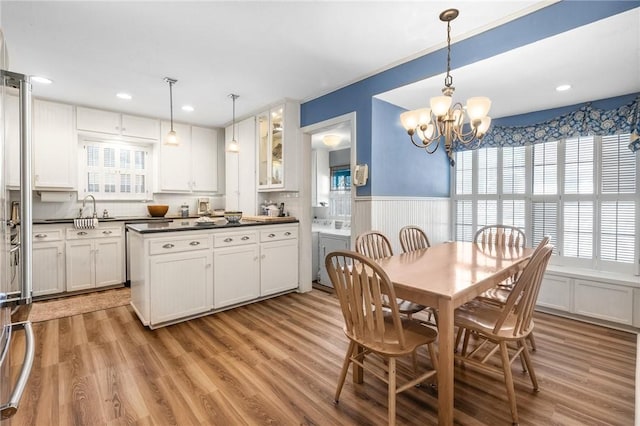 kitchen featuring dark countertops, a wainscoted wall, white cabinets, and a sink