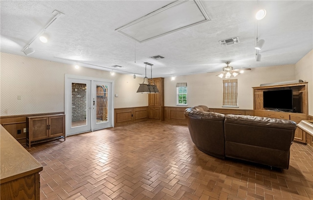 5222 Wooldridge, Corpus Christi, TX 78413 - living room featuring attic access, track lighting, a textured ceiling, a wainscoted wall, and ceiling fan