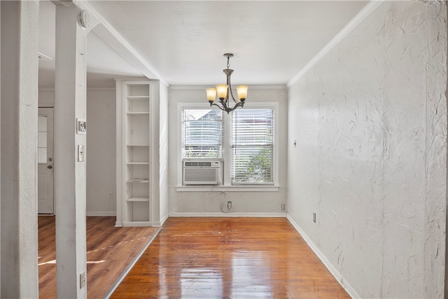 unfurnished dining area featuring cooling unit, hardwood / wood-style floors, a notable chandelier, and crown molding