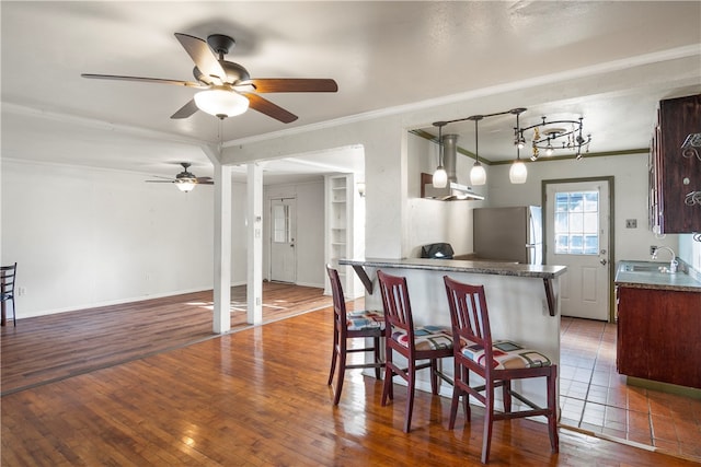 kitchen featuring dark hardwood / wood-style flooring, hanging light fixtures, a kitchen bar, and stainless steel fridge