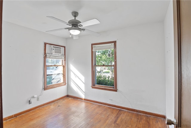 unfurnished room featuring light wood-type flooring, a wall unit AC, and ceiling fan