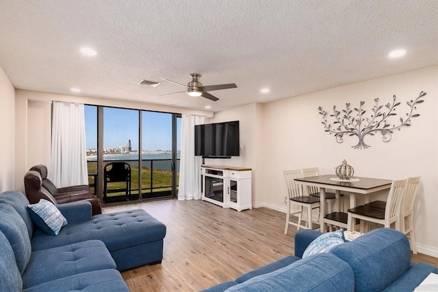 living room with floor to ceiling windows, ceiling fan, wood-type flooring, and a textured ceiling