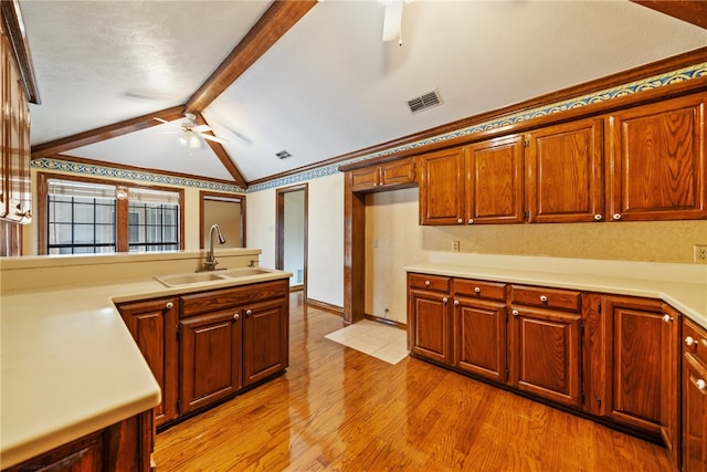 kitchen featuring vaulted ceiling with beams, a textured ceiling, sink, light hardwood / wood-style floors, and ceiling fan