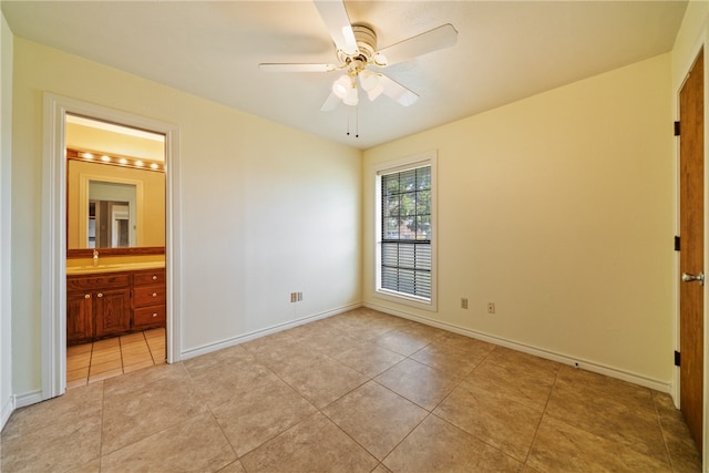 unfurnished bedroom with connected bathroom, light tile patterned floors, and ceiling fan