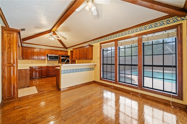 kitchen featuring lofted ceiling with beams, kitchen peninsula, ceiling fan, and light wood-type flooring