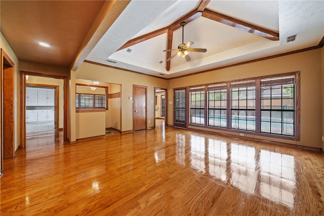 spare room featuring ceiling fan, a tray ceiling, vaulted ceiling with beams, crown molding, and light wood-type flooring