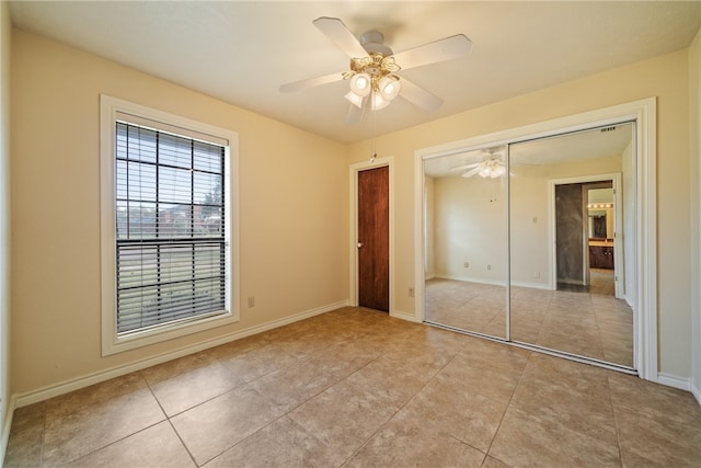 unfurnished bedroom with light tile patterned floors, ceiling fan, and a closet