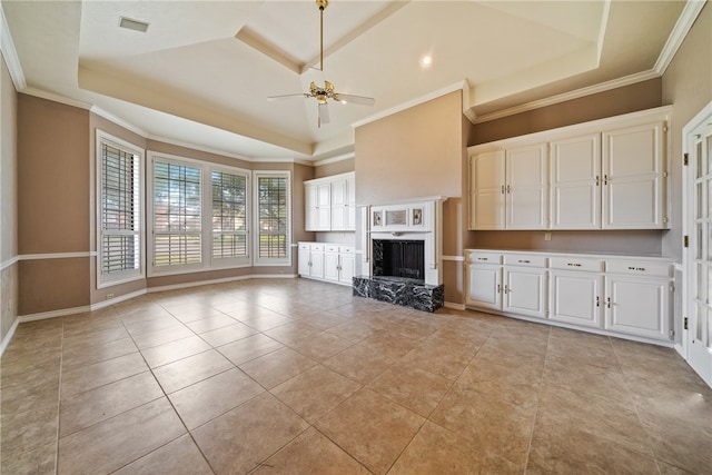 unfurnished living room featuring ceiling fan, ornamental molding, light tile patterned floors, and a tray ceiling