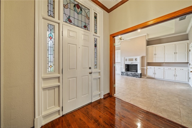 foyer entrance featuring hardwood / wood-style flooring, ceiling fan, a premium fireplace, and ornamental molding