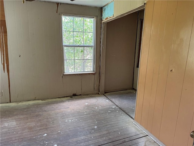 423 S 13th St, Kingsville, TX 78363 - unfurnished bedroom with wood walls, multiple windows, hardwood / wood-style floors, and a closet