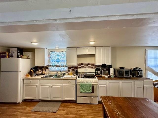 kitchen with sink, white appliances, light hardwood / wood-style flooring, and white cabinets