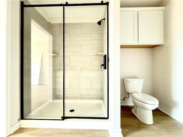 bathroom featuring a stall shower, baseboards, toilet, and wood finished floors