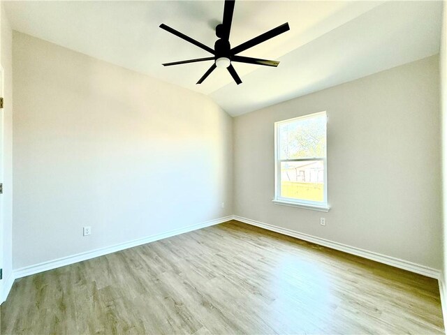 empty room with vaulted ceiling, ceiling fan, wood finished floors, and baseboards