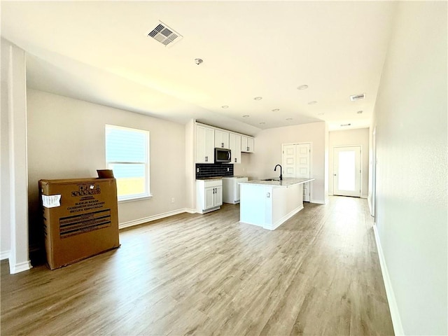 kitchen featuring a healthy amount of sunlight, white cabinetry, stainless steel microwave, and a sink