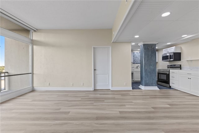 kitchen with white cabinetry, decorative columns, light hardwood / wood-style floors, and stainless steel appliances