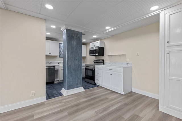 kitchen with stainless steel appliances, white cabinetry, sink, and light hardwood / wood-style flooring